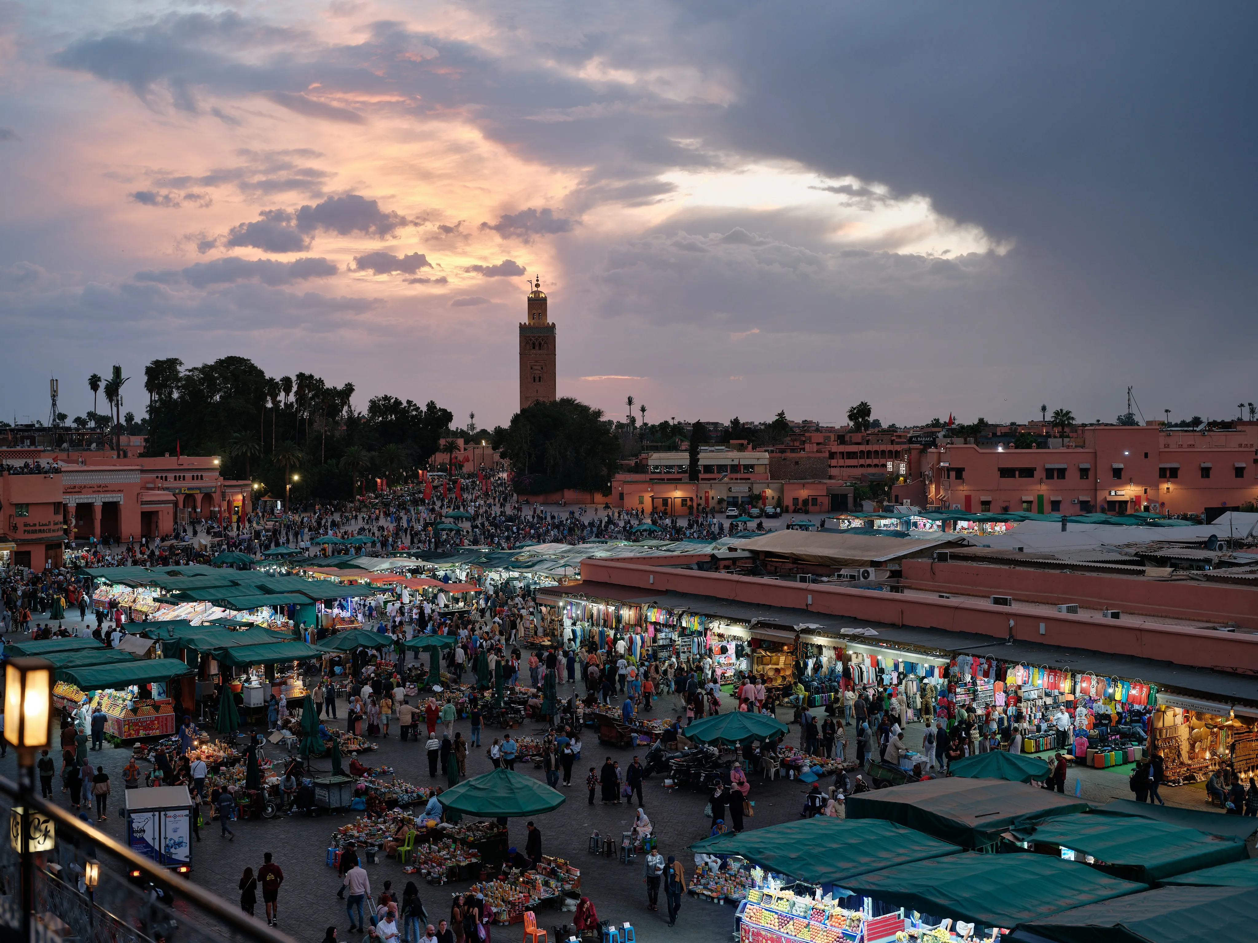 Orange sky over Jemaa el-Fna at golden hour, silhouettes of the crowd and the Koutoubia minaret