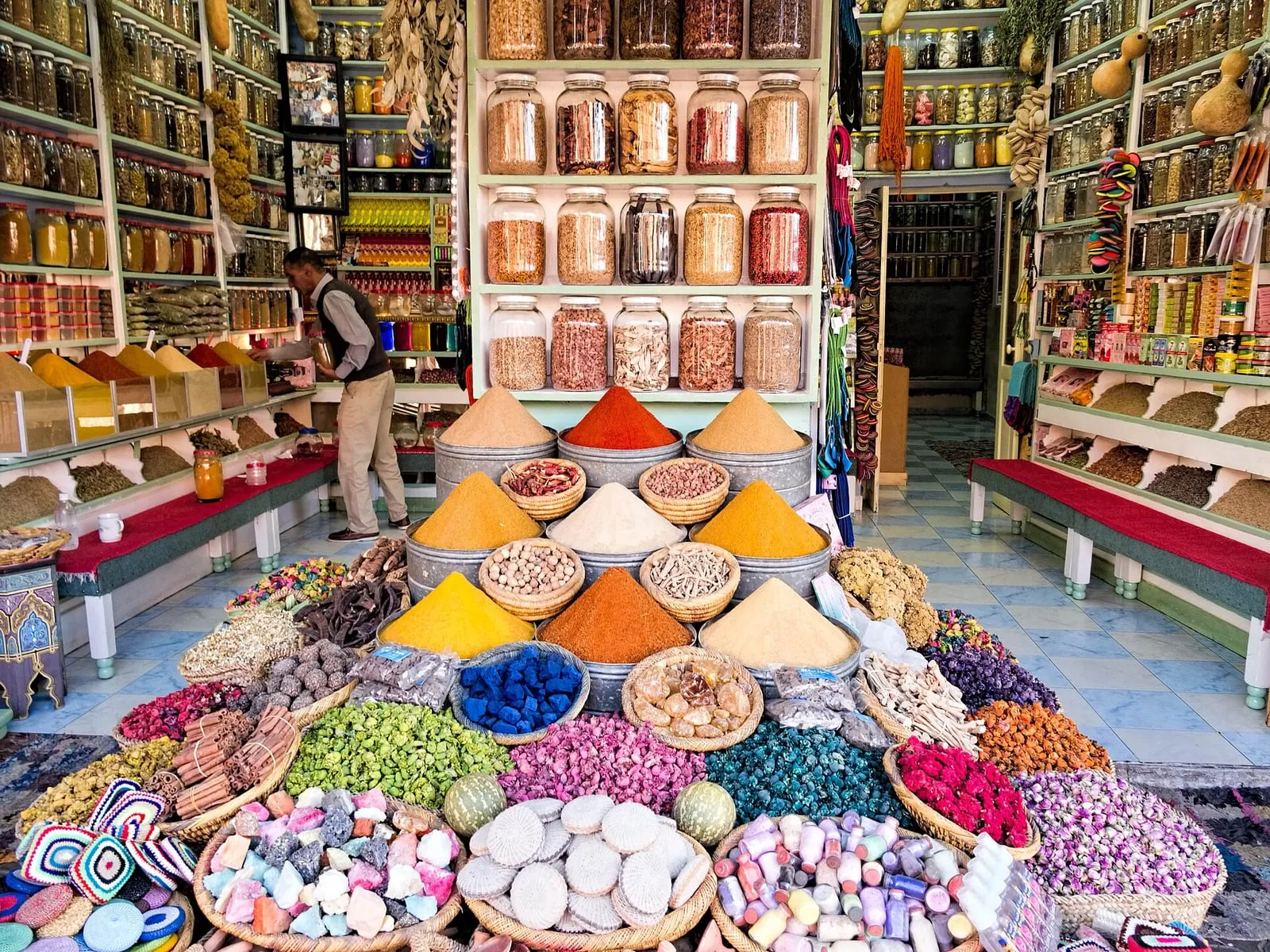 Échoppe d'herboriste dans les souks de Marrakech avec pyramides d'épices colorées, bocaux et savons